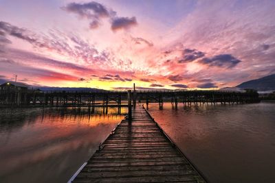 Pier over lake against sky during sunset