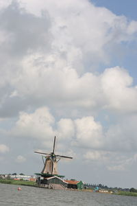 Traditional windmill by sea against sky