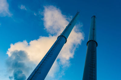 Low angle view of smokestacks against blue sky