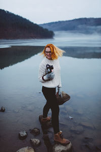 Full length of young woman standing on rock in lake