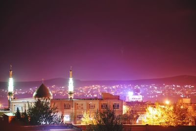 Illuminated buildings against sky at night