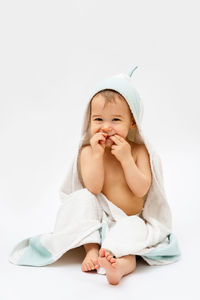 Portrait of cute baby girl sitting against white background