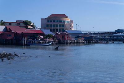 Buildings by sea against clear sky