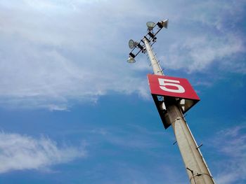 Low angle view of information sign on pole against sky