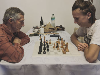 Side view of people playing chess on table