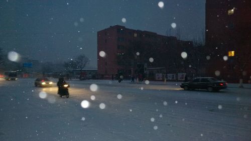 Cars on illuminated city during winter