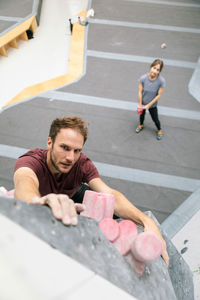 High angle portrait of man practicing rock climbing at gym