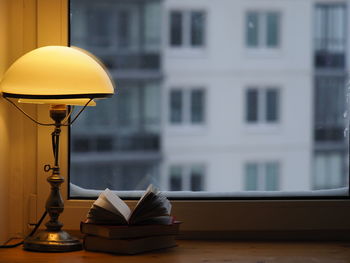 Snowstorm window apartment building. warm light vintage lamp, books. winter evening care of yourself