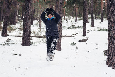 Full length of boy playing with snow in forest