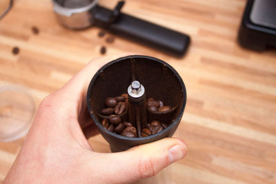 High angle view of hand holding coffee beans on table