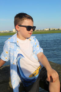 Boy wearing sunglasses on sea against sky