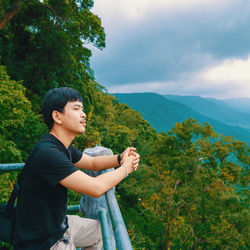 Side view of man looking at mountains against sky