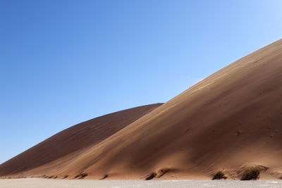 Sand dunes in desert against clear blue sky