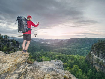 Rear view of man standing on rock against sky