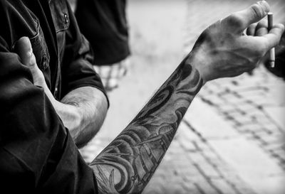 Midsection of tattooed man holding cigarette