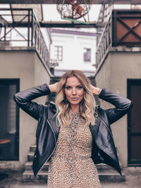 Portrait of young woman standing against wall