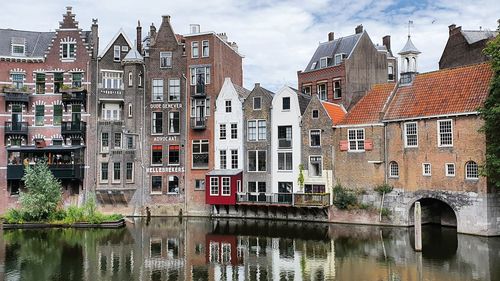 Buildings by canal against sky in city