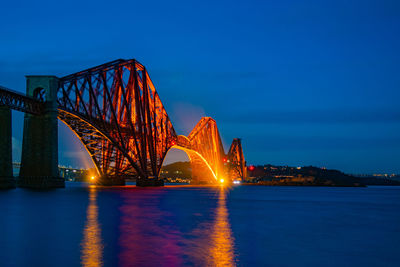 Illuminated bridge over river at night