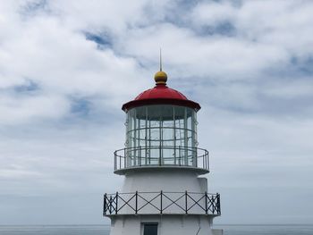 Lighthouse by sea against sky