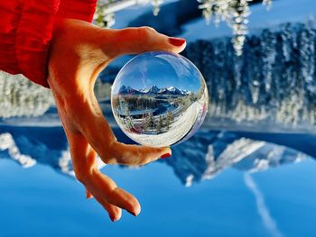 Midsection of person holding crystal ball in water