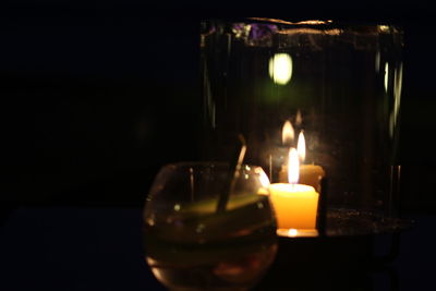 Close-up of lit tea light candles in darkroom