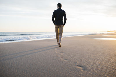 Rear view of man walking at beach