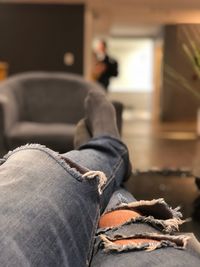 Low section of person wearing torn jeans at home