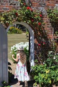  girl standing by flowering plants and doorway