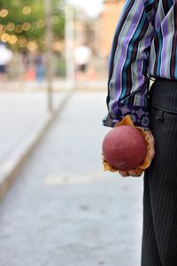 Midsection of man holding ice cream standing outdoors