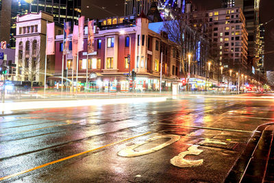 Light trails on road against buildings in city at night