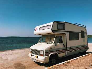 Vintage car on beach against clear blue sky