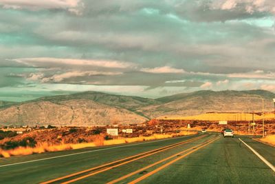 Road by mountains against sky