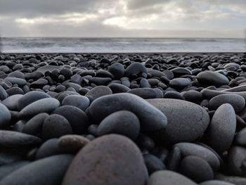 Close-up of pebbles at beach against sky