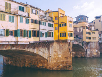 Arch bridge over river against buildings in city