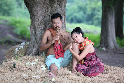 Woman sitting on tree trunk against plants