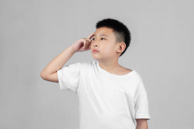 Boy looking away while standing against white background