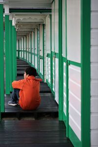 Boy sitting on wooden structure