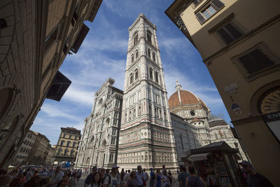 Low angle view of crowd outside buildings against sky