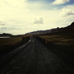 Country road against cloudy sky