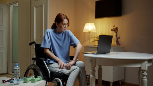 Young woman sitting on wheelchair at home