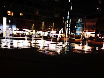 Boats in illuminated city at night