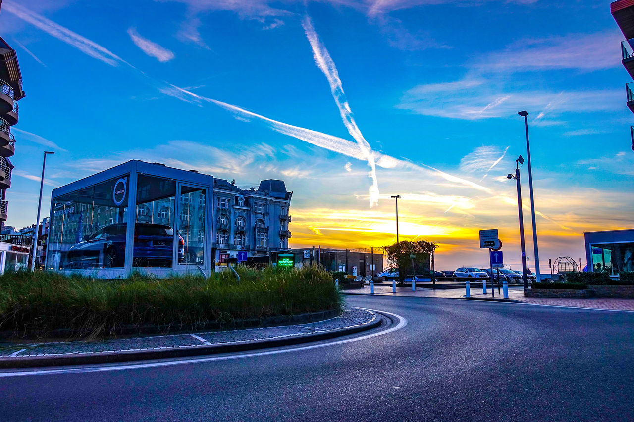 ROAD BY BUILDINGS AGAINST BLUE SKY