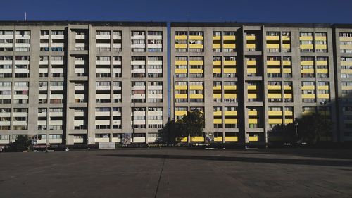 Residential buildings by street against clear sky