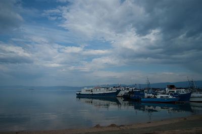 Boats in sea against cloudy sky