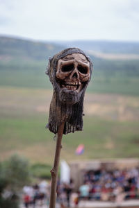 Close-up of human skull on wooden post against sky