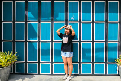 Portrait of smiling young woman standing against door