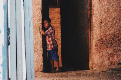 Full length of boy standing against wall