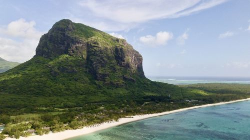 Scenic view of sea by mountain against sky