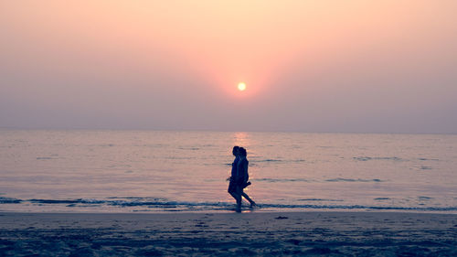 Woman on beach against sky during sunset