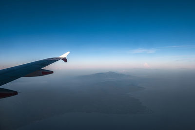 Airplane flying over mountains against blue sky